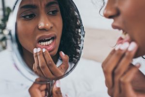 woman looking at her gums in the mirror